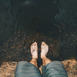 Low section of people standing on sand at sea