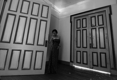 Portrait of woman standing against window in building