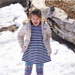 Portrait of smiling girl standing on snow covered field