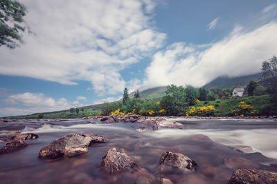 Scenic view of river by mountains against sky