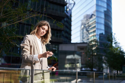 Young woman standing against buildings