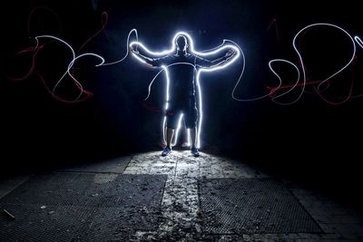 Full length of man standing against illuminated lights at night