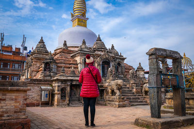 Full length rear view of woman standing against temple and sky