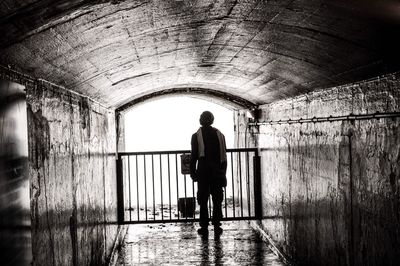 Full length of man standing in wet abandoned tunnel