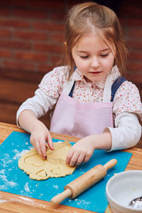 Girl preparing cookie at table