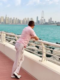 Rear view of man on boat in city against sky