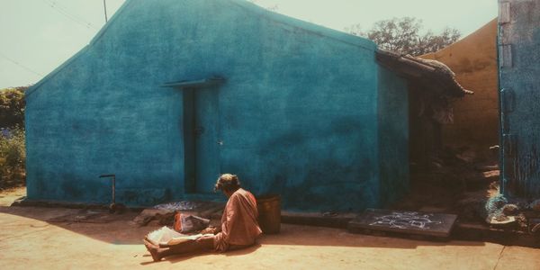Rear view of woman sitting against building