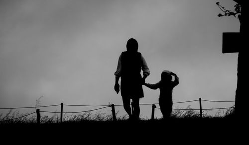 Silhouette couple standing on field against sky