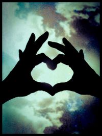 Low angle view of hands heart shape against sky