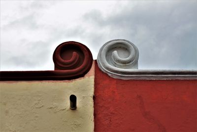 Low angle view of pipes on wall against sky