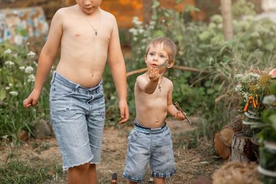 Full length of shirtless boy standing outdoors