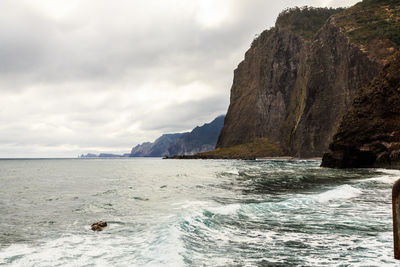 Scenic view of sea and mountains against cloudy sky