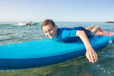 Portrait of boy in sea against blue sky