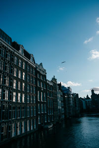 Buildings by river against sky