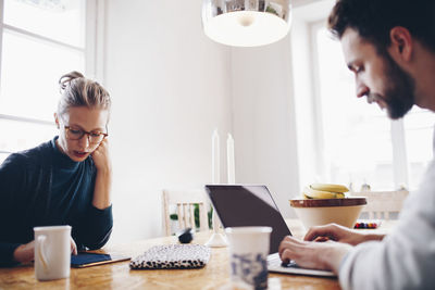 Couple using technologies at dining table while working from home