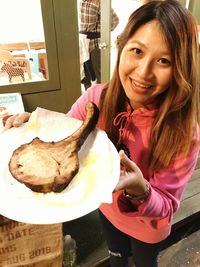 Portrait of smiling young woman standing by food