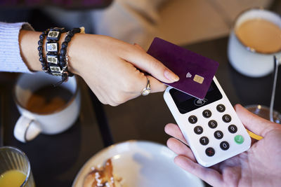 Young woman paying with card in cafe