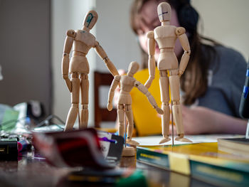 Close-up of wooden figurines with girl in background at home