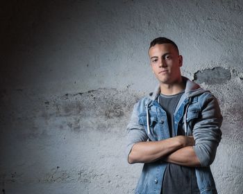 Portrait of young man standing against wall