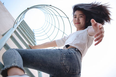 Low angle portrait of woman climbing on ladder