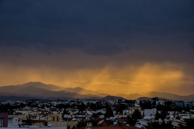 Houses in town against sky during sunset