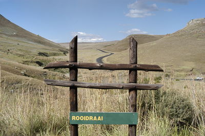 Information sign on wooden post on field against sky