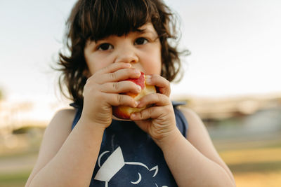 Close-up portrait of girl eating apple outdoors