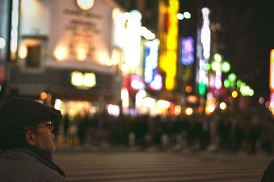 Man at city street against illuminated buildings at night