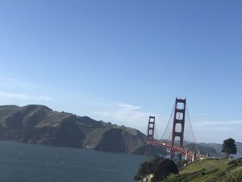 Suspension bridge over sea against sky