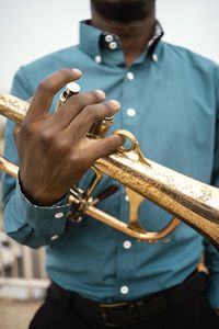 Midsection of man holding saxophone