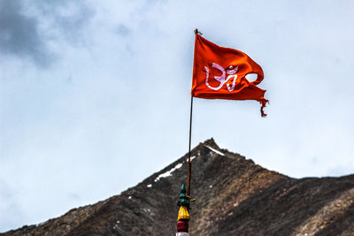 Low angle view of flag on mountain against sky