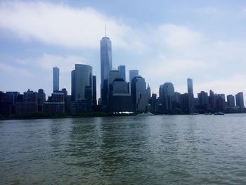 Sea by modern buildings against sky in city