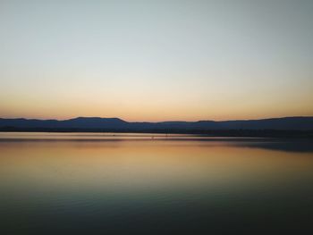 Scenic view of lake against clear sky during sunset