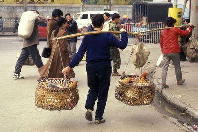 Rear view of people standing in basket on street