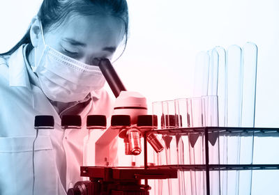 Scientist looking through microscope telescope against white background