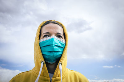 Close-up of woman wearing flu mask looking away standing outdoors