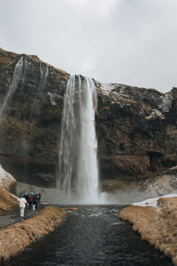 Rear view of man standing against waterfall