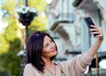 Young beautiful woman smiling going to the shops using smartphone