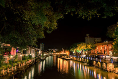 River by illuminated city against sky at night