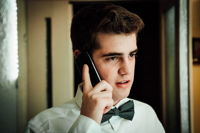 Young man looking away while talking on mobile phone