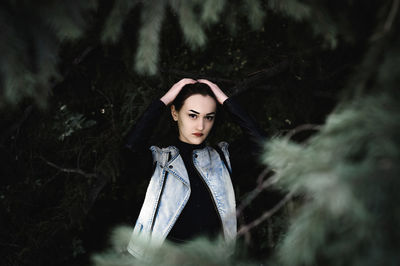 Portrait of young woman standing by trees