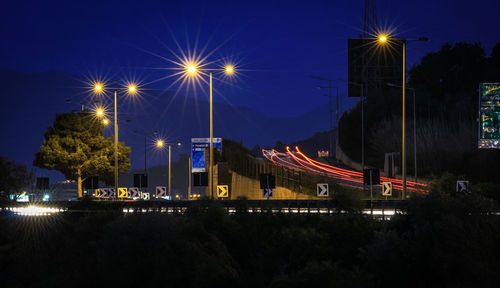 Light trails on street against sky at night