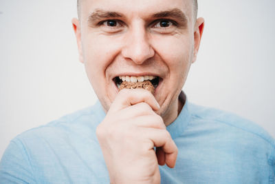 Close-up portrait of man eating against white background