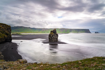 Scenic view of rocks on shore against sky