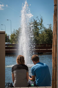 Rear view of people sitting on fountain