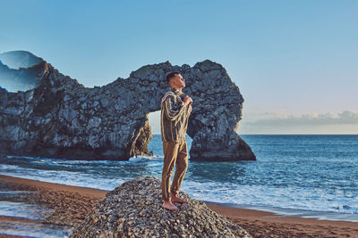 Young man standing on rock at beach