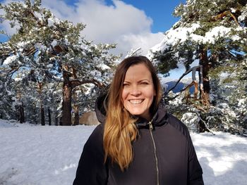 Portrait of smiling young woman standing in snow