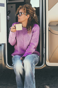 Young woman using mobile phone while sitting on sofa at home