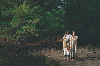 Couple standing by tree in forest