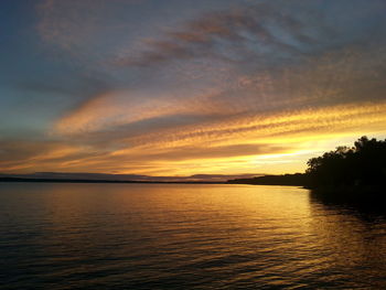 Scenic view of sea against cloudy sky at sunset